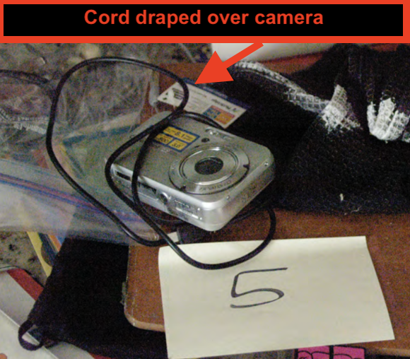 Zoom — Sony Cybershot placed on cluttered countertop with its cord draped over it