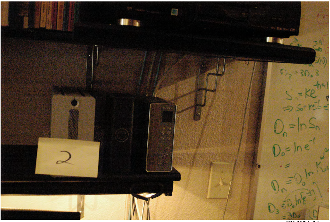 FBI search photo — bookshelf with Item 2, three devices, plain background (IMAGE TO BE ADDED)